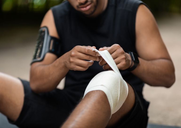 Person bandaging an injured knee